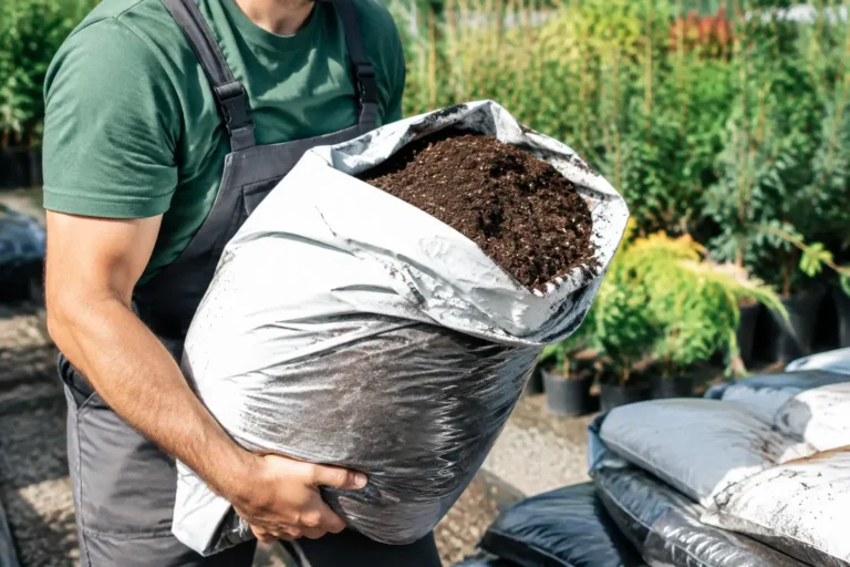 Un jardinier manipule un sac de terreau lourd dont la densité du terreau varie selon l'humidité